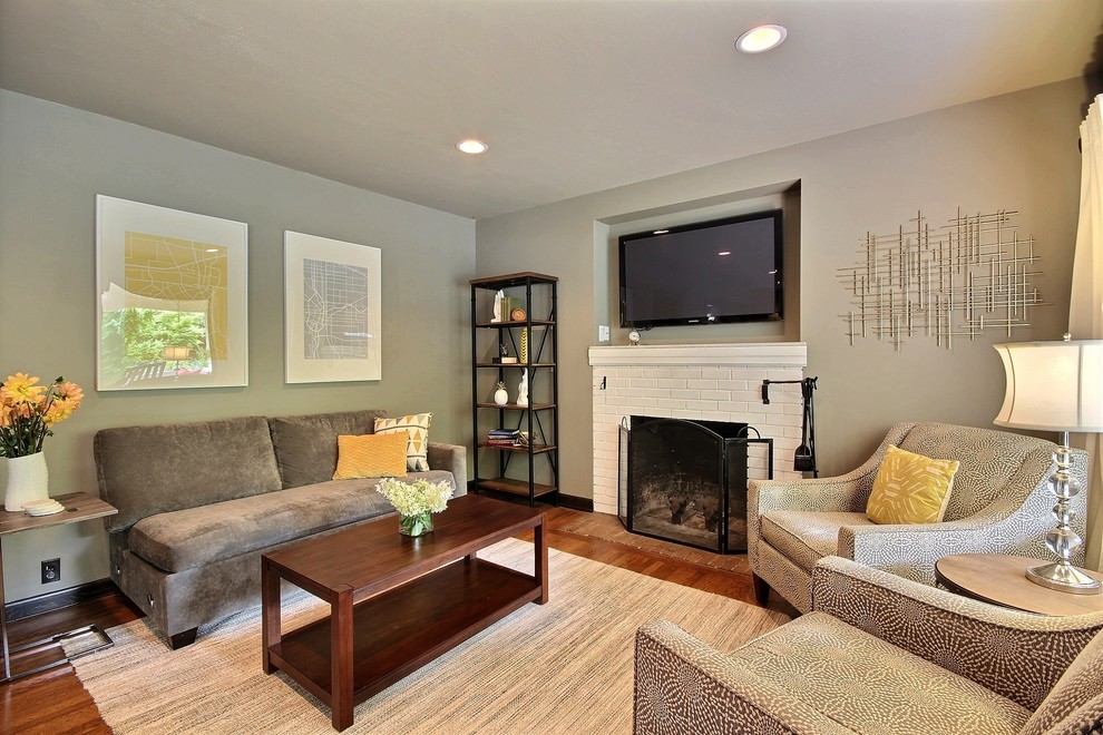 Photo of a mid-sized arts and crafts open concept family room in Portland with grey walls, a wall-mounted tv, dark hardwood floors, a standard fireplace, a brick fireplace surround and brown floor.