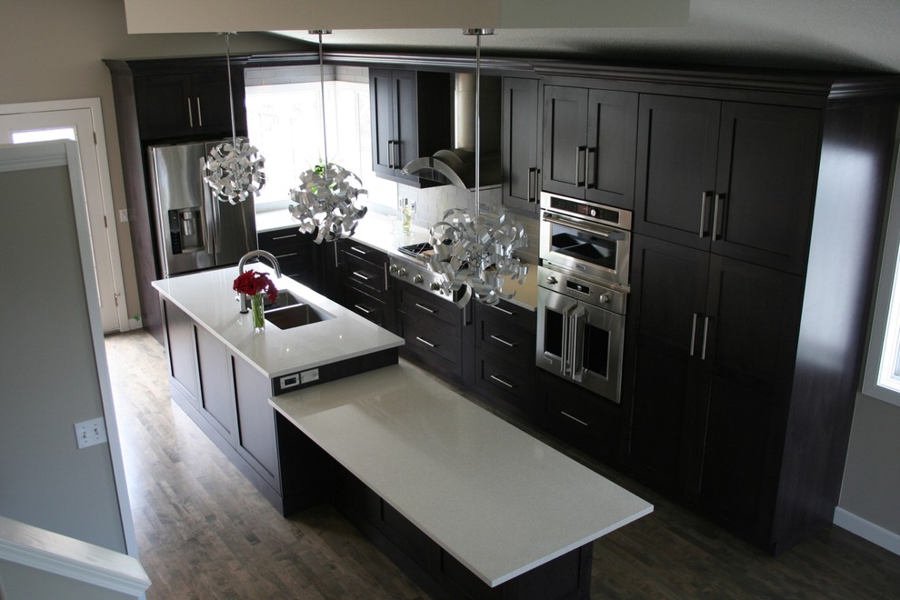 Example of a mid-sized transitional l-shaped dark wood floor open concept kitchen design in Calgary with a triple-bowl sink, shaker cabinets, dark wood cabinets, quartz countertops, gray backsplash, glass tile backsplash, stainless steel appliances and an island