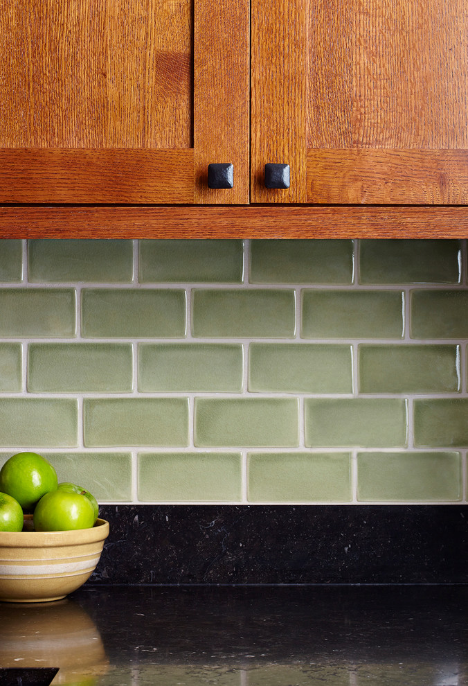 Photo of a small arts and crafts u-shaped eat-in kitchen in New York with an undermount sink, shaker cabinets, light wood cabinets, granite benchtops, green splashback, subway tile splashback, stainless steel appliances and porcelain floors.