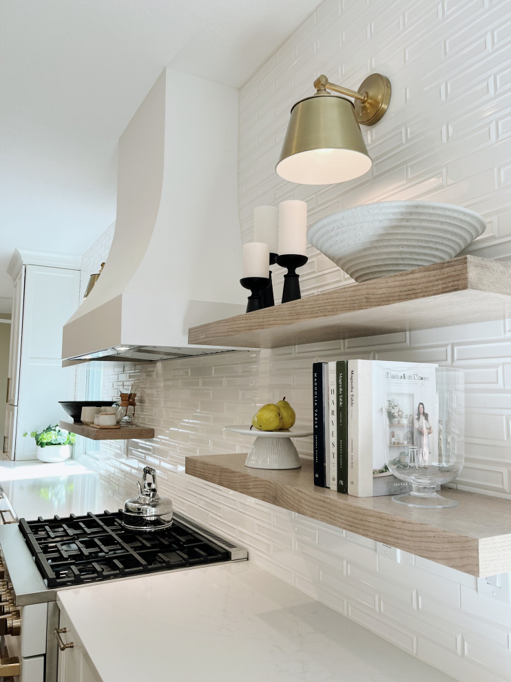 Example of a large transitional l-shaped light wood floor and beige floor eat-in kitchen design with a farmhouse sink, shaker cabinets, white cabinets, quartz countertops, white backsplash, ceramic backsplash, white appliances, an island and white countertops