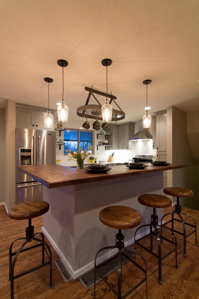 Eat-in kitchen - mid-sized transitional l-shaped medium tone wood floor eat-in kitchen idea in Denver with a farmhouse sink, shaker cabinets, gray cabinets, quartz countertops, white backsplash, ceramic backsplash, stainless steel appliances and an island