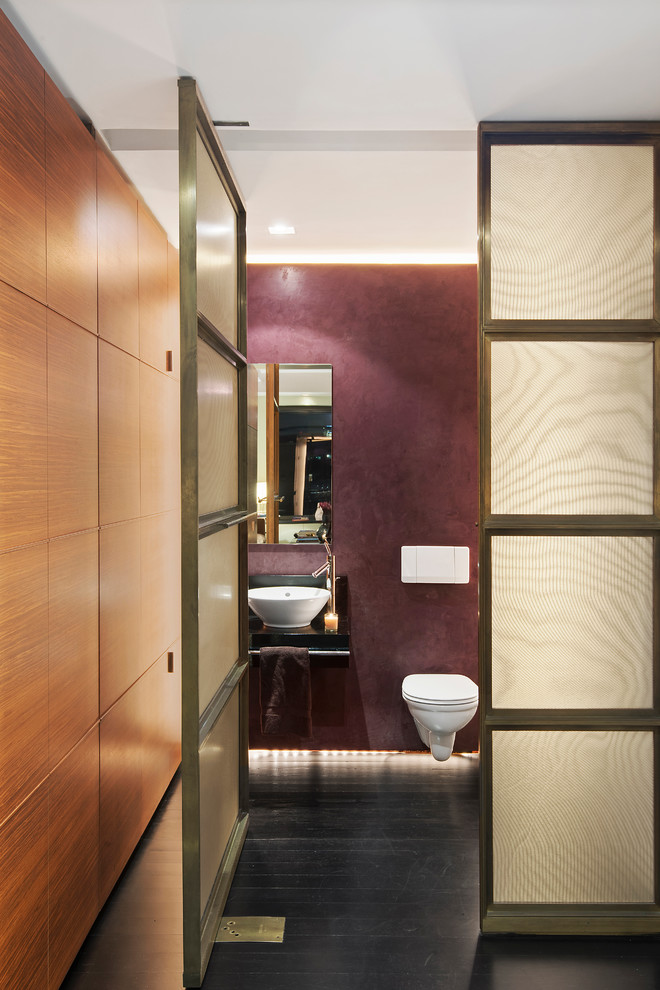 Photo of a mid-sized contemporary powder room in New York with a vessel sink, a wall-mount toilet, purple walls and dark hardwood floors.