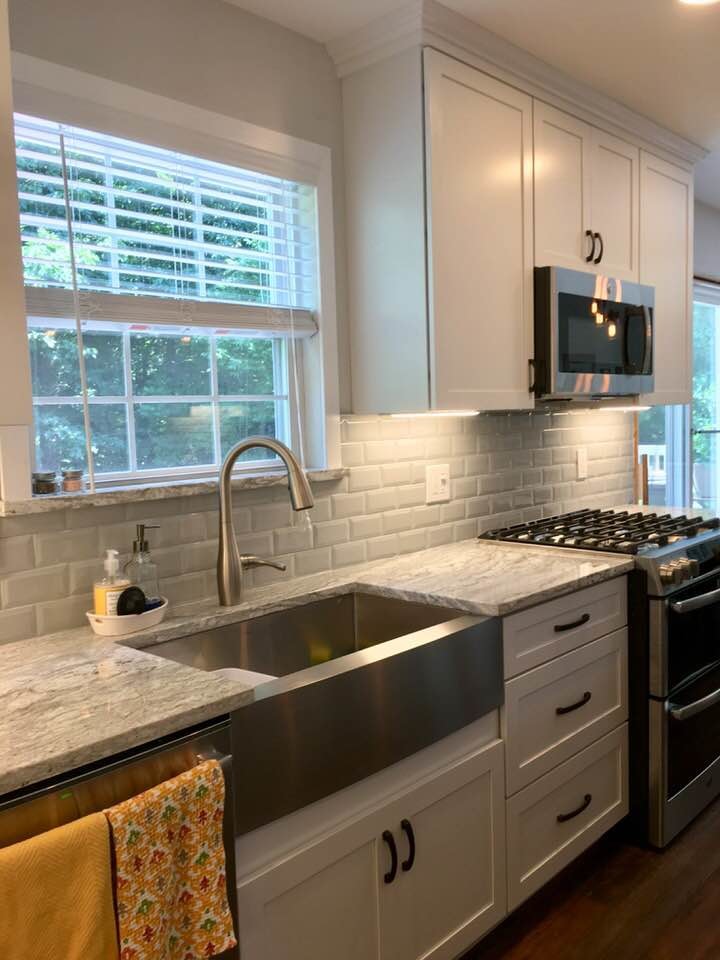 Mid-sized contemporary u-shaped eat-in kitchen in Wilmington with a farmhouse sink, recessed-panel cabinets, white cabinets, granite benchtops, grey splashback, ceramic splashback, stainless steel appliances, dark hardwood floors, with island, brown floor and grey benchtop.