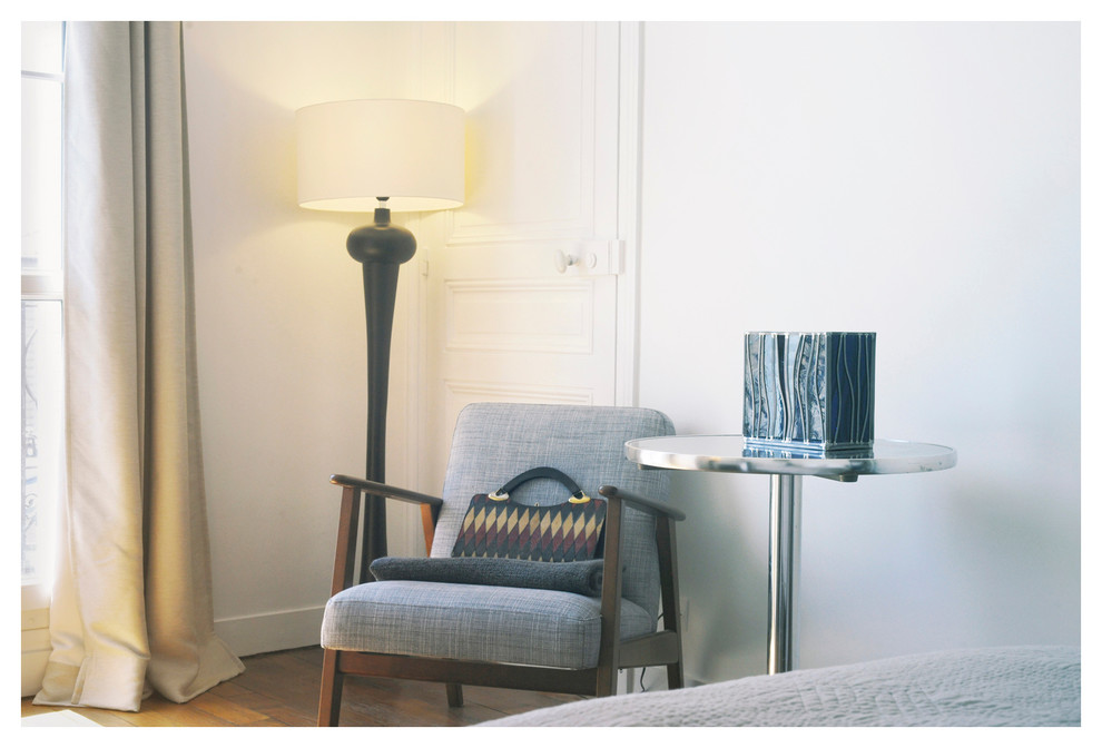 This is an example of a mid-sized transitional bedroom in Paris with white walls and light hardwood floors.