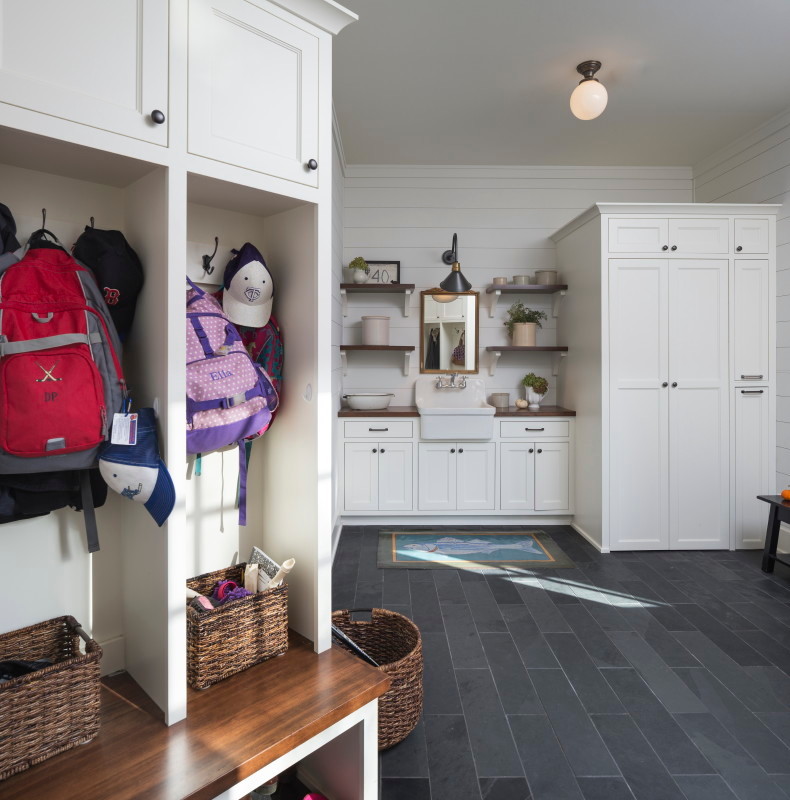 Eclectic mudroom with white walls and grey floor.