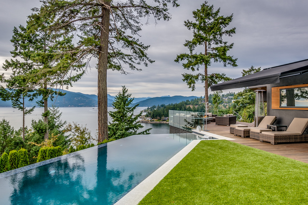 This is an example of a contemporary rooftop custom-shaped infinity pool in Vancouver with decking.