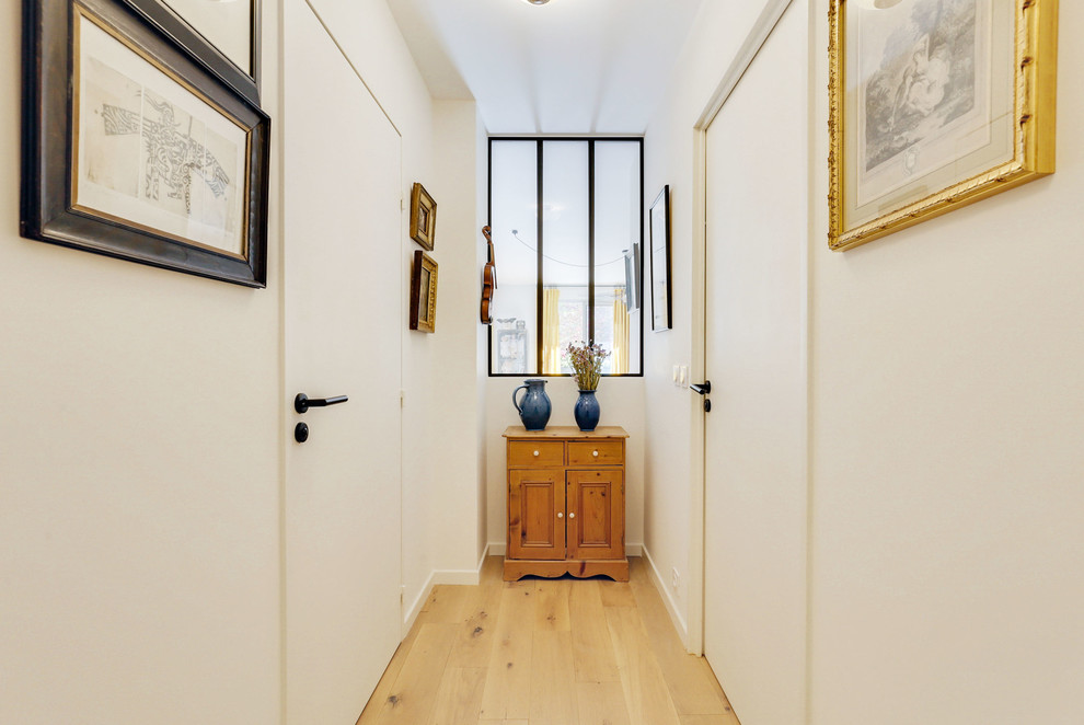Inspiration for a small contemporary hallway in Paris with white walls, light hardwood floors and beige floor.