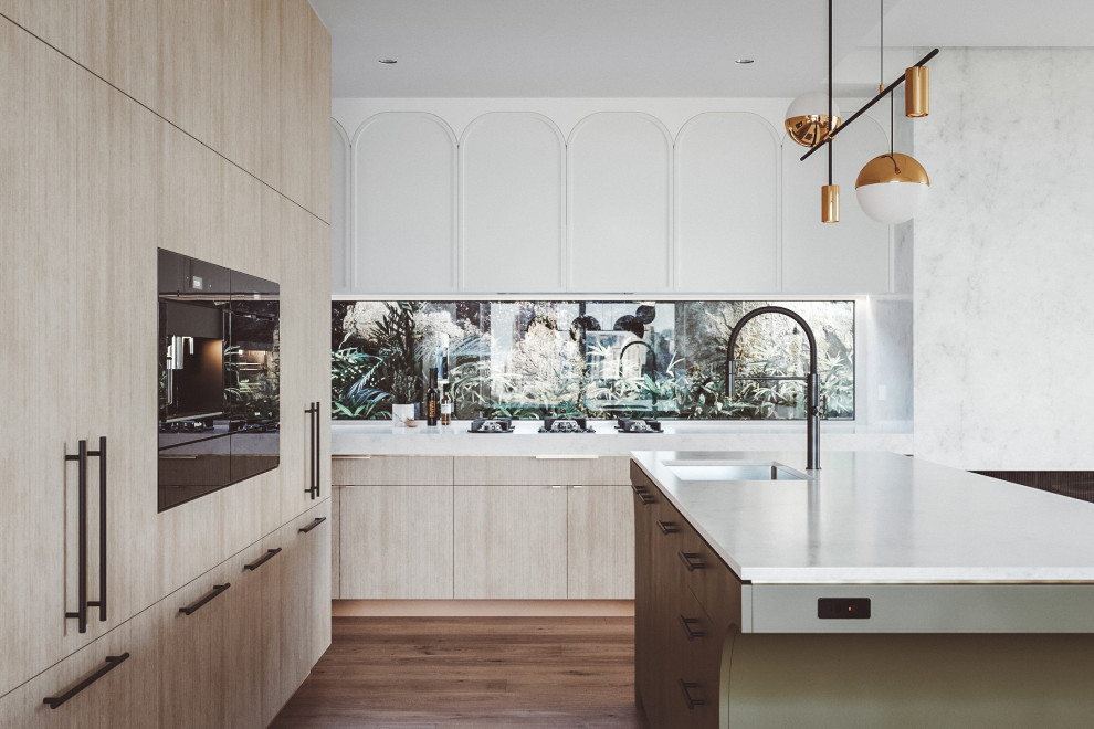 Inspiration for a mid-sized contemporary galley open plan kitchen with an undermount sink, shaker cabinets, light wood cabinets, marble benchtops, white splashback, marble splashback, black appliances, medium hardwood floors, with island, brown floor, white benchtop and recessed.