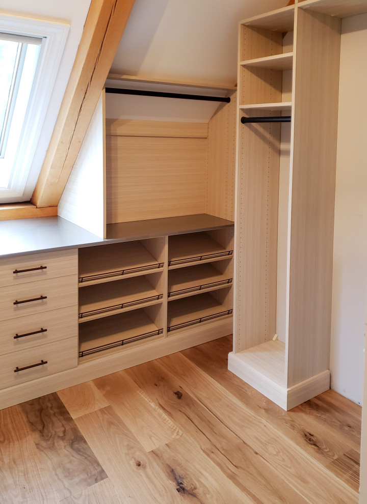 Inspiration for a mid-sized walk-in closet remodel in Burlington with flat-panel cabinets and light wood cabinets