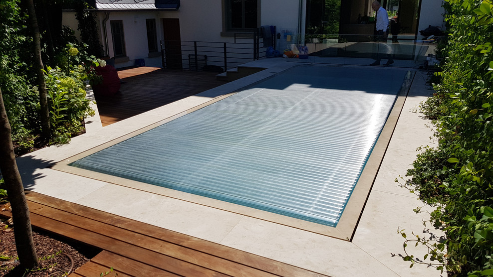 This is an example of a mid-sized contemporary backyard rectangular infinity pool in Frankfurt with natural stone pavers.