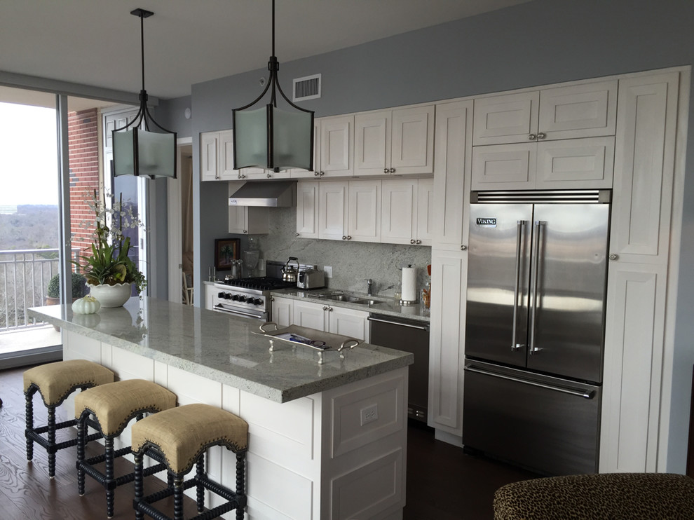 Inspiration for a mid-sized transitional single-wall dark wood floor and brown floor eat-in kitchen remodel in Atlanta with an undermount sink, recessed-panel cabinets, white cabinets, granite countertops, gray backsplash, stone slab backsplash, stainless steel appliances and an island