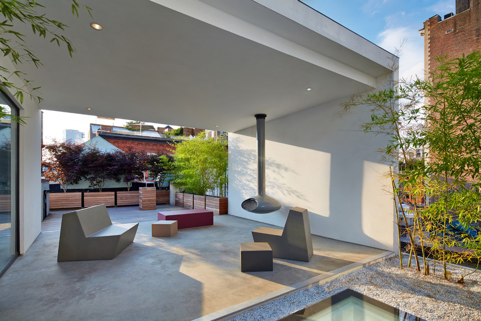 Mid-sized modern courtyard patio in New York with a fire feature, a roof extension and concrete slab.