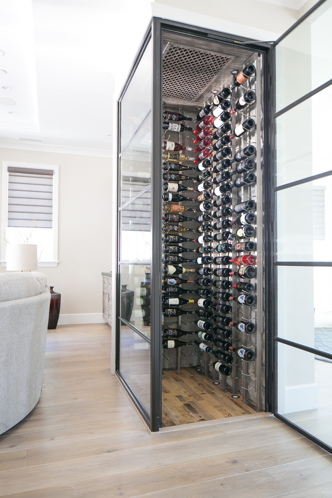 This is an example of a small contemporary wine cellar in Orange County with medium hardwood floors, storage racks and beige floor.