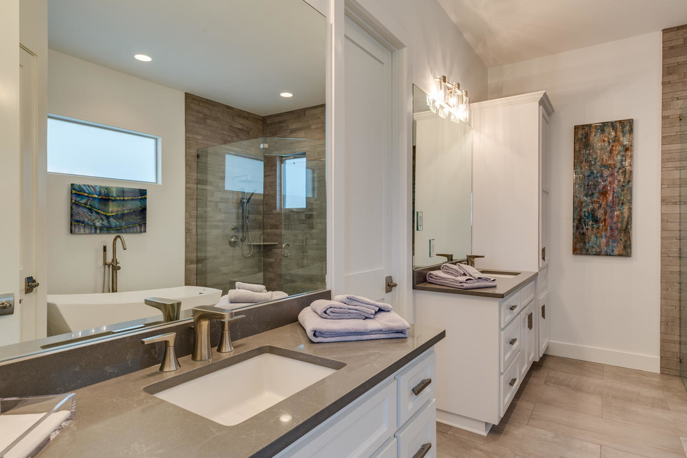 Design ideas for a large contemporary master bathroom in Austin with recessed-panel cabinets, white cabinets, a freestanding tub, a corner shower, beige tile, stone tile, white walls, porcelain floors, an undermount sink, beige floor and a hinged shower door.