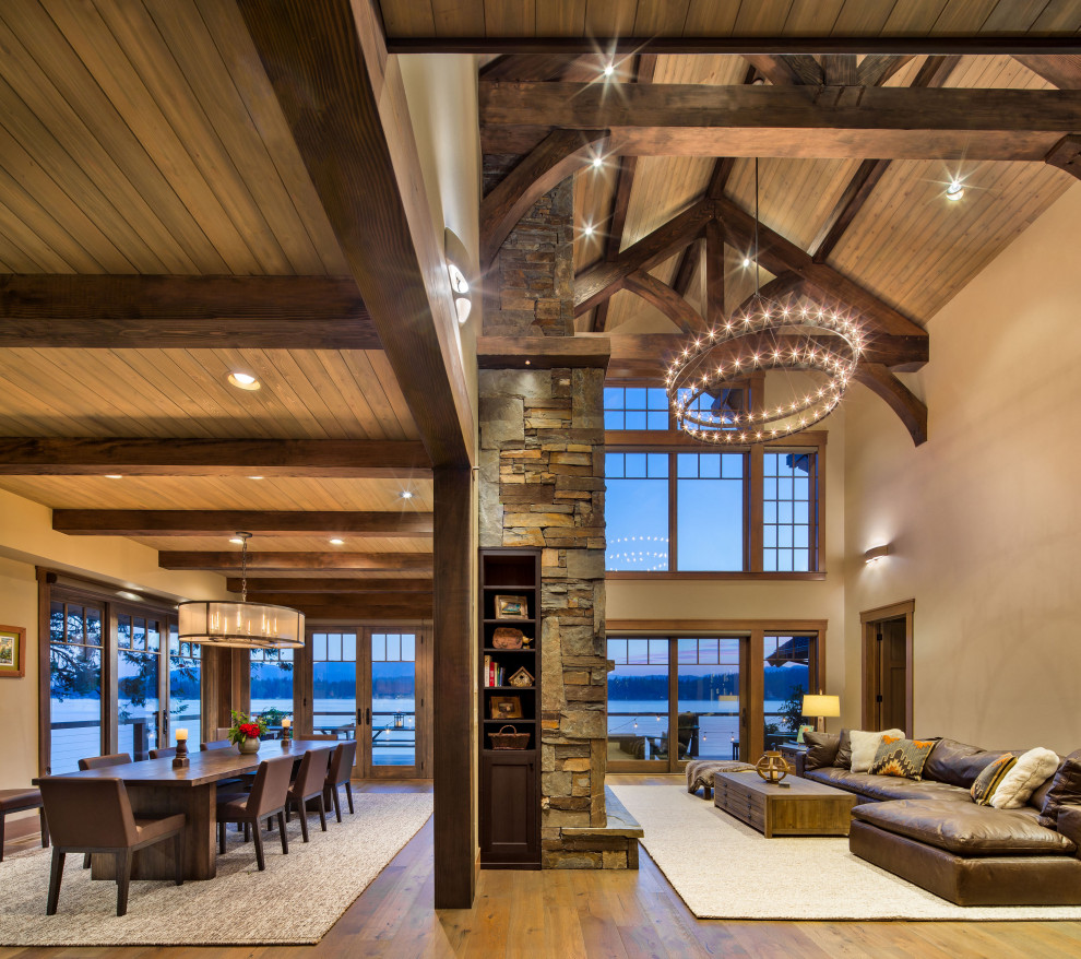 Inspiration for a mid-sized country open concept living room in Seattle with medium hardwood floors, a standard fireplace, a stone fireplace surround, beige floor, vaulted and beige walls.