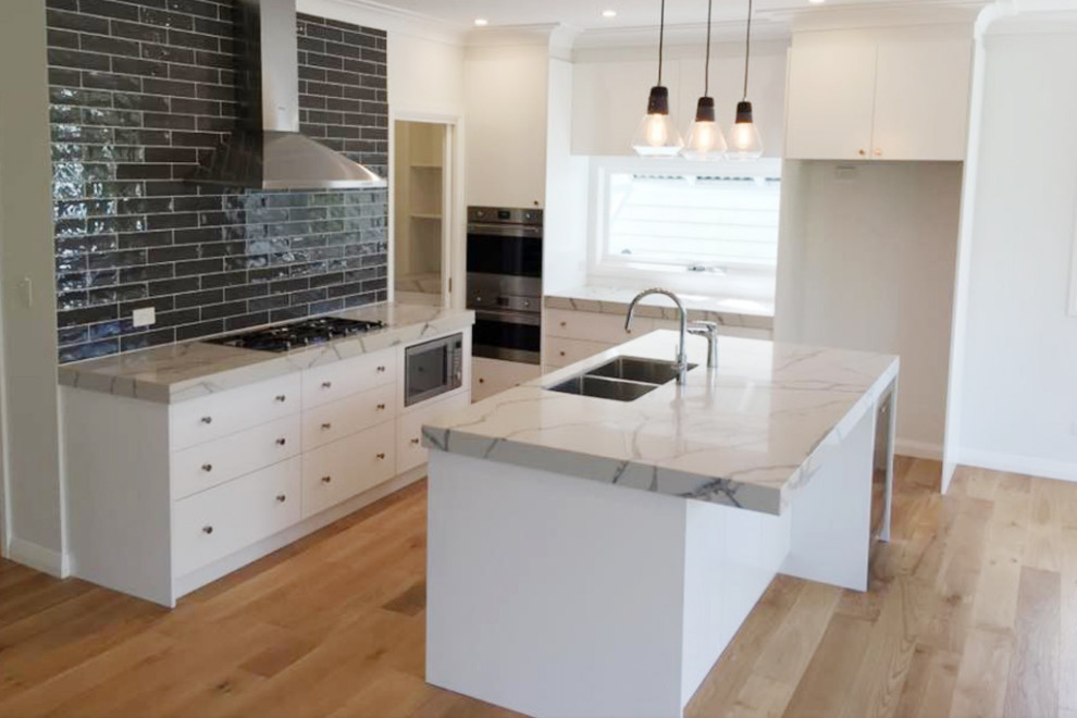 Photo of a mid-sized contemporary galley eat-in kitchen in Sydney with a double-bowl sink, louvered cabinets, white cabinets, marble benchtops, black splashback, subway tile splashback, dark hardwood floors, with island, brown floor and grey benchtop.