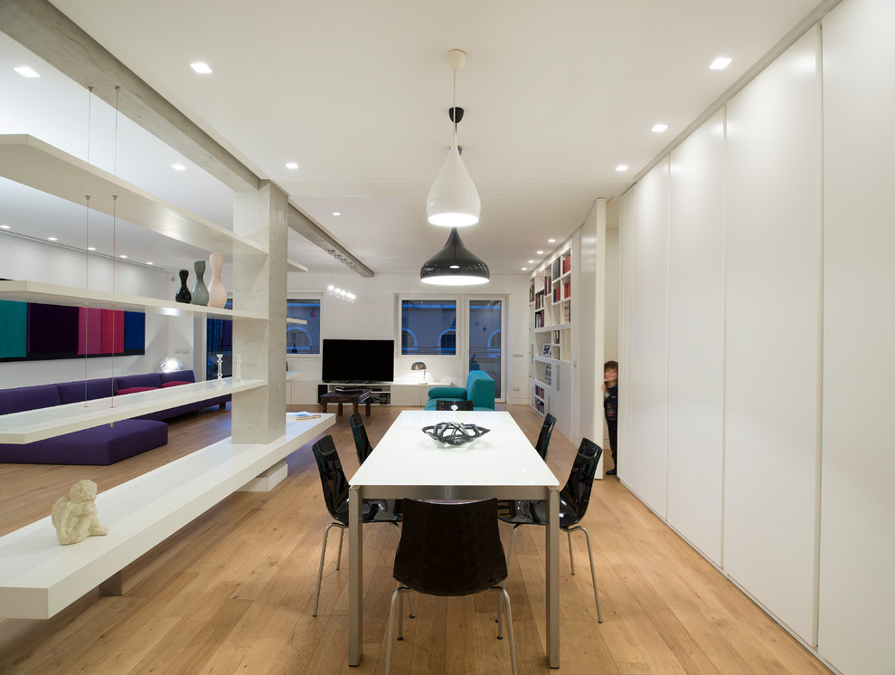 This is an example of a contemporary open plan dining in Rome with white walls and medium hardwood floors.