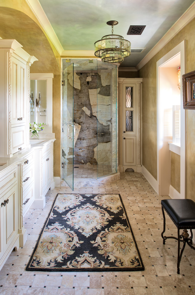 This is an example of an arts and crafts master bathroom in Minneapolis with recessed-panel cabinets, beige cabinets, a corner shower, multi-coloured tile, stone slab, an undermount sink, multi-coloured floor, a hinged shower door and beige benchtops.