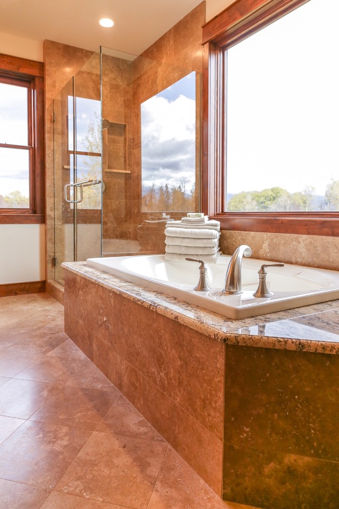 Photo of a large arts and crafts master bathroom in Other with raised-panel cabinets, medium wood cabinets, a drop-in tub, a corner shower, beige tile, stone tile, white walls, porcelain floors, an undermount sink, granite benchtops, brown floor, a hinged shower door and multi-coloured benchtops.
