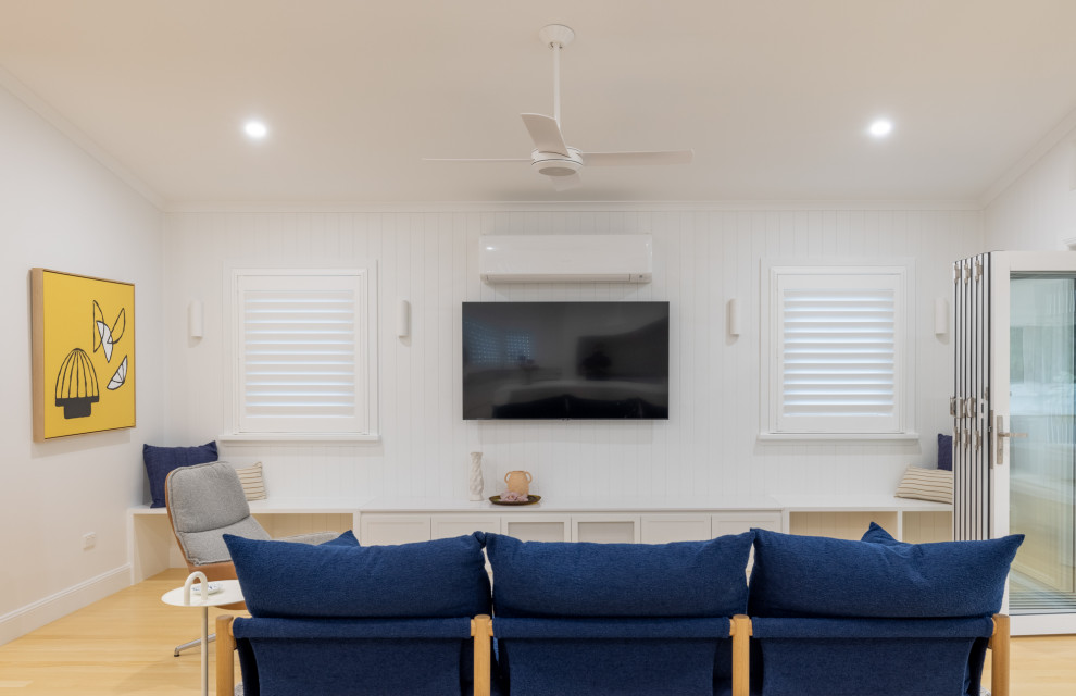 Design ideas for a mid-sized beach style open concept living room in Townsville with a library, white walls, light hardwood floors and wood walls.