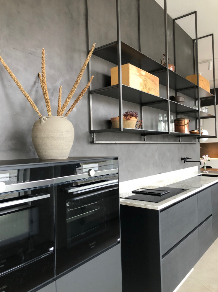 Photo of a mid-sized scandinavian single-wall eat-in kitchen in Malmo with a single-bowl sink, flat-panel cabinets, black cabinets, quartz benchtops, beige splashback, black appliances, concrete floors, no island, grey floor and beige benchtop.