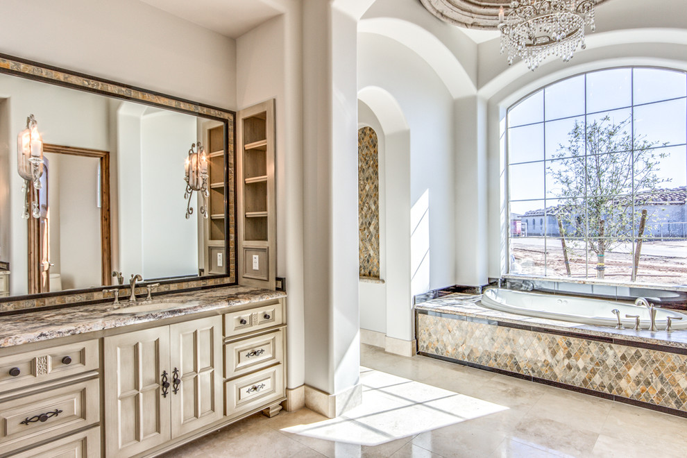 Inspiration for a large traditional master bathroom in Phoenix with raised-panel cabinets, light wood cabinets, a drop-in tub, beige tile, stone tile, beige walls, travertine floors, an undermount sink and granite benchtops.