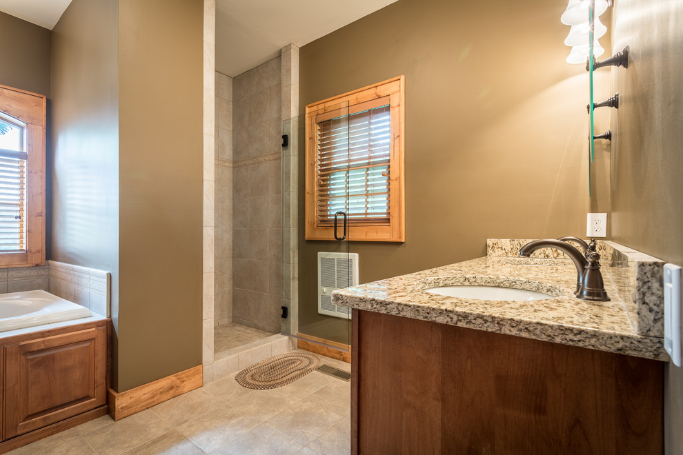 Inspiration for a mid-sized country master bathroom in Charlotte with an undermount sink, raised-panel cabinets, medium wood cabinets, granite benchtops, a drop-in tub, an alcove shower, beige tile, ceramic tile, beige walls and ceramic floors.