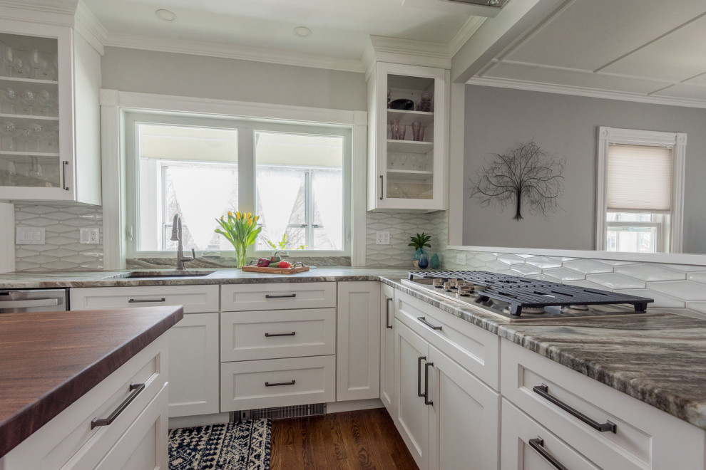 Mid-sized transitional u-shaped medium tone wood floor and brown floor eat-in kitchen photo in Boston with an undermount sink, shaker cabinets, white cabinets, quartzite countertops, gray backsplash, ceramic backsplash, stainless steel appliances, an island and multicolored countertops