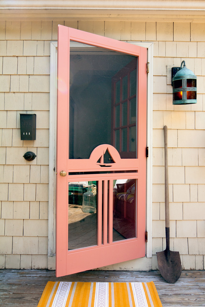 This is an example of a beach style entryway in Portland Maine with a single front door and an orange front door.