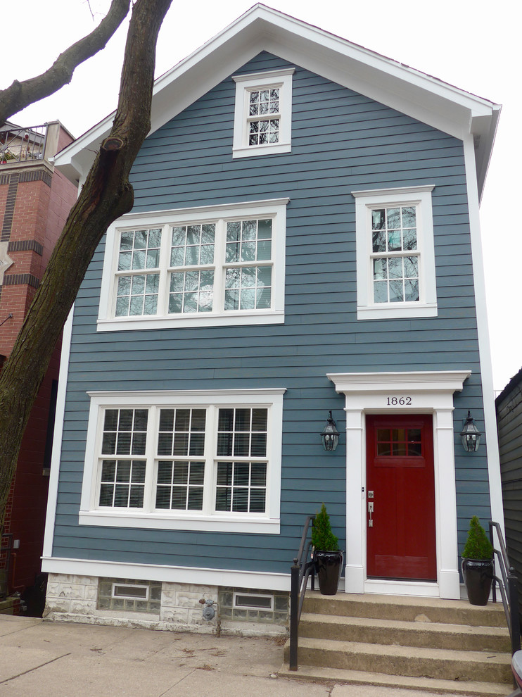This is an example of a mid-sized traditional two-storey blue house exterior in Chicago with concrete fiberboard siding, a shingle roof and a gable roof.