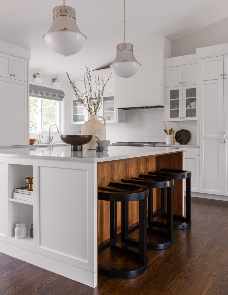 Inspiration for a large transitional l-shaped open plan kitchen in Seattle with an undermount sink, white cabinets, quartz benchtops, white splashback, subway tile splashback, stainless steel appliances, medium hardwood floors, with island, brown floor, white benchtop and shaker cabinets.