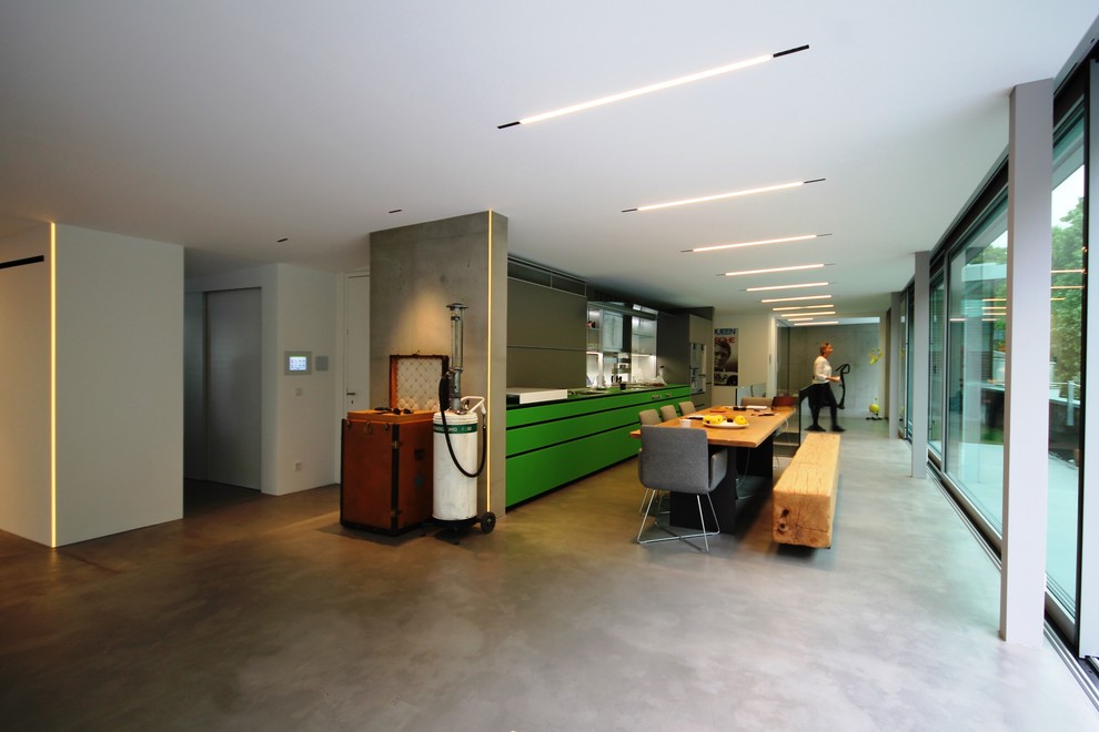 Offene, Einzeilige, Geräumige Industrial Küche ohne Insel mit integriertem Waschbecken, grünen Schränken, Mineralwerkstoff-Arbeitsplatte, Küchenrückwand in Grau, Küchengeräten aus Edelstahl und Betonboden in Stuttgart
