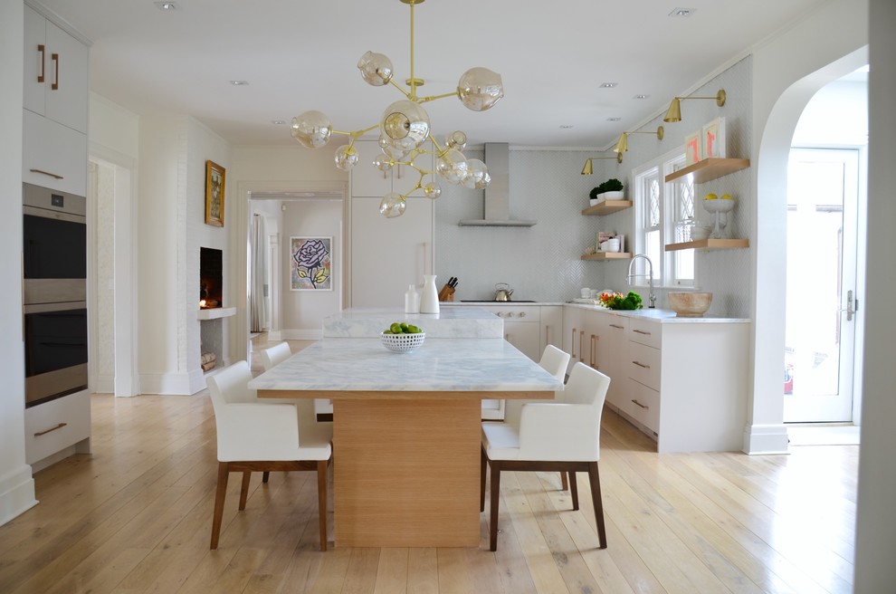 Design ideas for a transitional u-shaped kitchen in New York with flat-panel cabinets, white cabinets, white splashback, mosaic tile splashback, panelled appliances, light hardwood floors, with island and beige floor.
