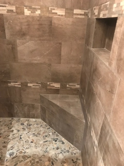 Example of a transitional brown tile and marble tile corner shower design in Denver