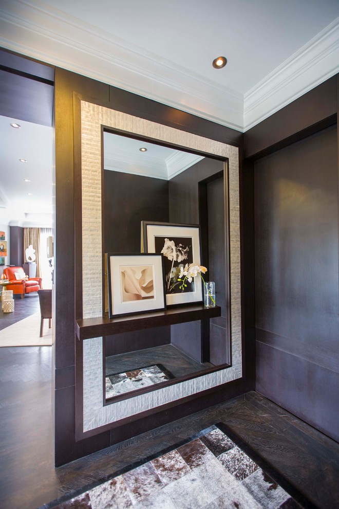 This is an example of a small modern foyer in DC Metro with brown walls, dark hardwood floors and a dark wood front door.