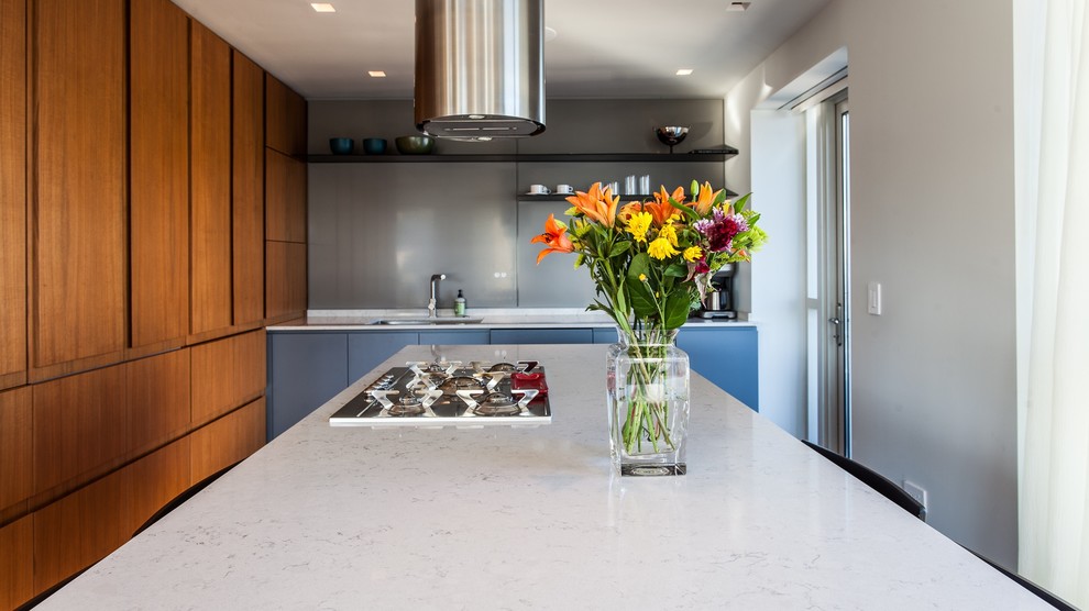 Example of a mid-sized minimalist l-shaped medium tone wood floor and brown floor eat-in kitchen design in Chicago with an undermount sink, flat-panel cabinets, medium tone wood cabinets, quartz countertops, gray backsplash, glass sheet backsplash, stainless steel appliances and an island