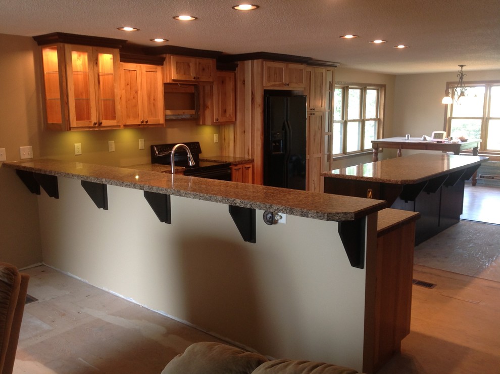 Mid-sized l-shaped open concept kitchen photo with raised-panel cabinets, light wood cabinets, laminate countertops, black appliances and a peninsula
