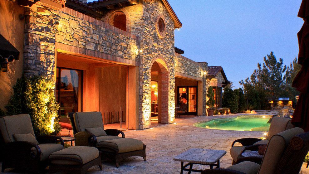 Photo of a large mediterranean backyard full sun xeriscape in Las Vegas with natural stone pavers.