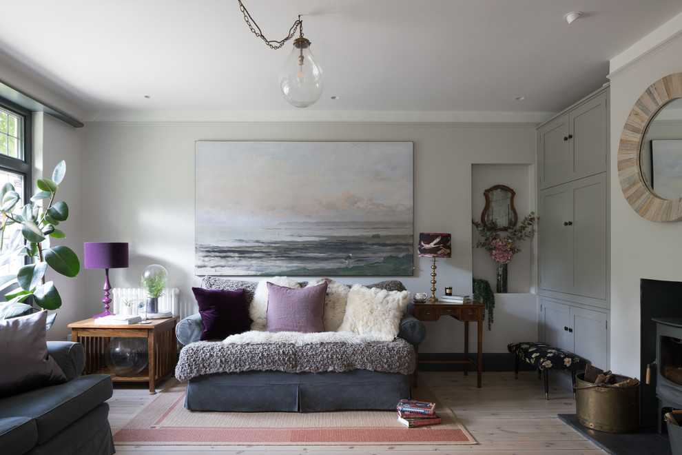 Design ideas for a mid-sized arts and crafts formal enclosed living room in Hertfordshire with grey walls, a wood stove, a plaster fireplace surround, a concealed tv and white floor.