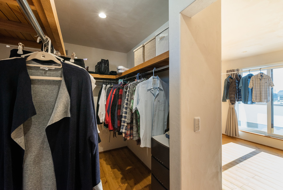 This is an example of an asian gender-neutral walk-in wardrobe in Other with open cabinets, medium hardwood floors and multi-coloured floor.