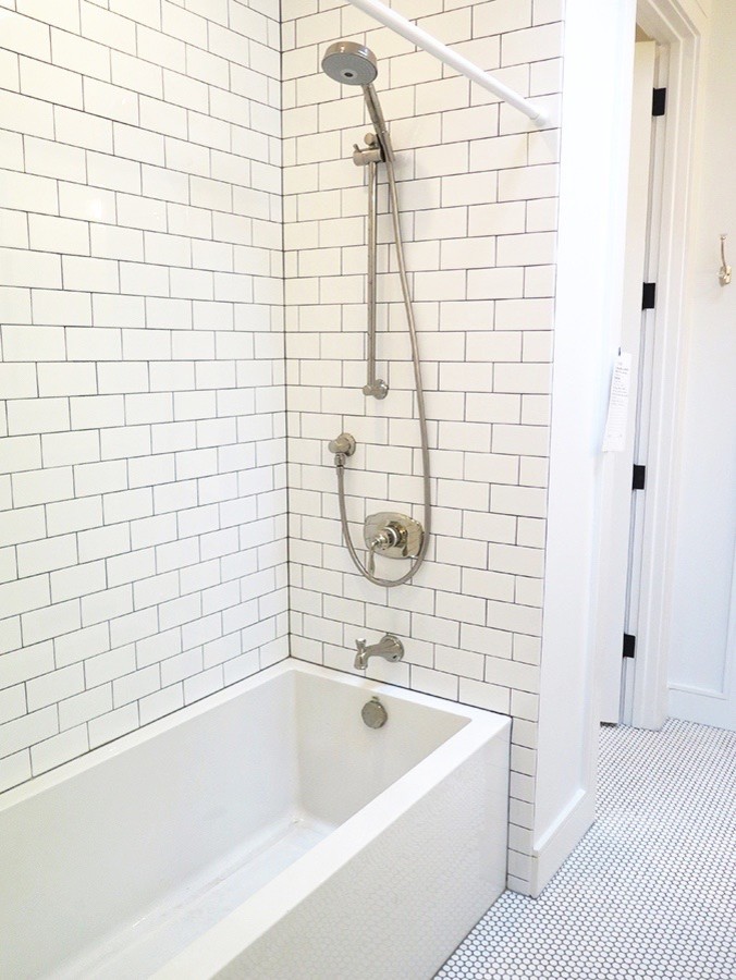 This is an example of an expansive industrial 3/4 bathroom in DC Metro with a corner tub, a corner shower, black and white tile, glass tile, white walls, ceramic floors and marble benchtops.