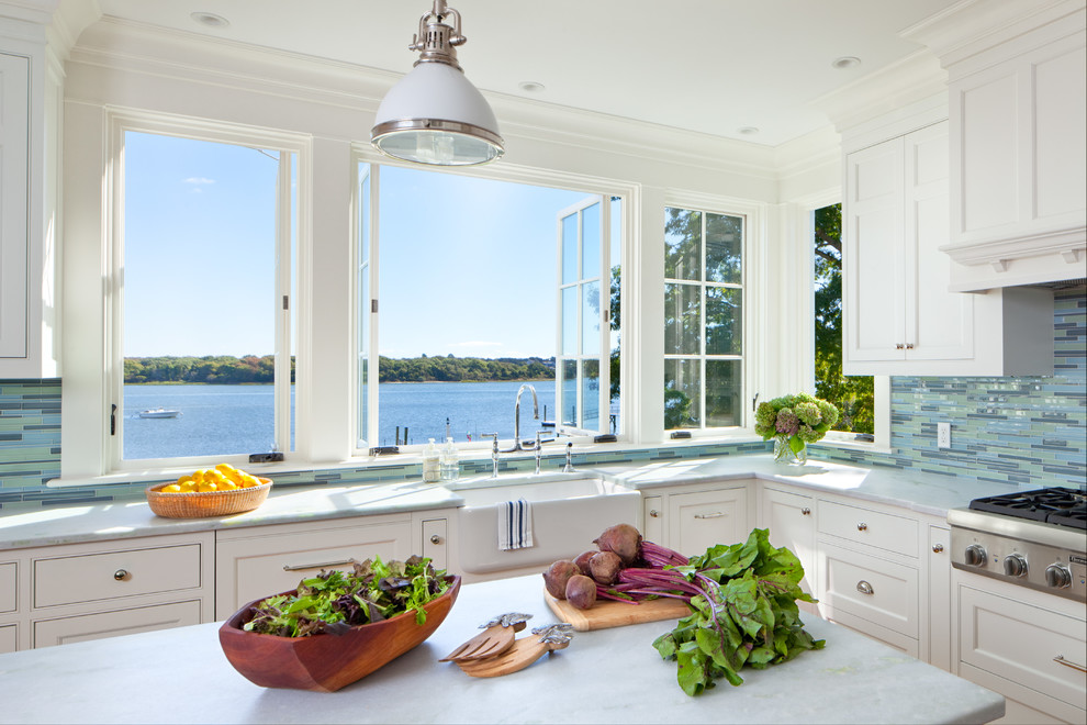 Inspiration for a beach style l-shaped kitchen in Providence with a farmhouse sink, shaker cabinets, white cabinets, multi-coloured splashback, matchstick tile splashback, stainless steel appliances and with island.