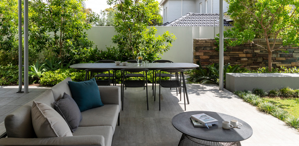 Inspiration for a mid-sized contemporary backyard patio in Perth with natural stone pavers and a roof extension.