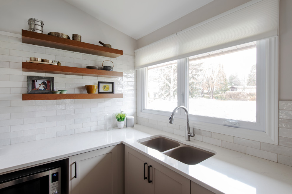 Open concept kitchen - mid-sized transitional l-shaped medium tone wood floor, gray floor and vaulted ceiling open concept kitchen idea in Ottawa with a double-bowl sink, shaker cabinets, gray cabinets, quartz countertops, white backsplash, subway tile backsplash, stainless steel appliances, an island and white countertops
