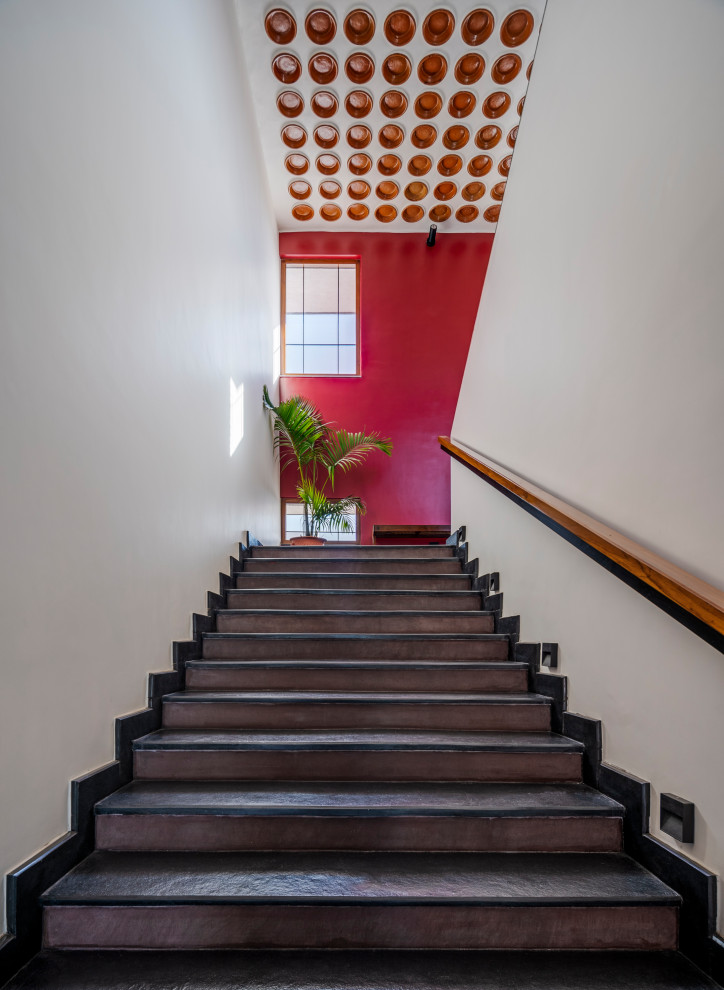 ハイデラバードにある高級な広いコンテンポラリースタイルのおしゃれな直階段 (ライムストーンの蹴込み板、木材の手すり、羽目板の壁) の写真