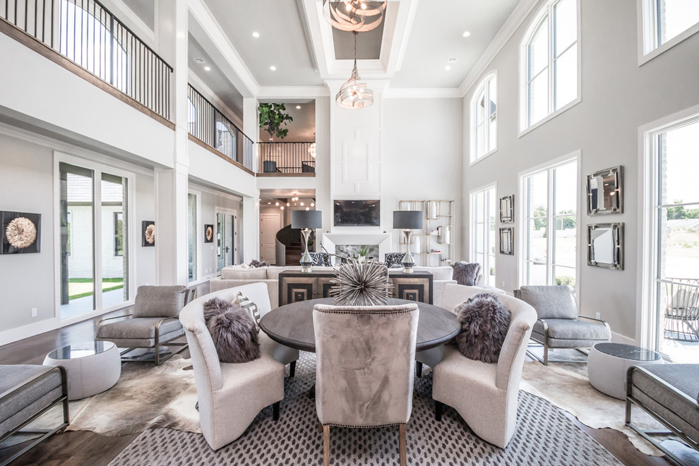 This is an example of an expansive transitional open plan dining in Other with grey walls, medium hardwood floors, a two-sided fireplace, a tile fireplace surround and brown floor.