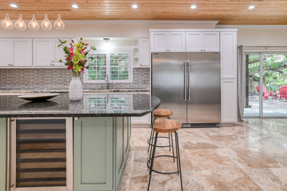 Photo of a mid-sized eclectic u-shaped eat-in kitchen with an undermount sink, recessed-panel cabinets, turquoise cabinets, granite benchtops, metal splashback, stainless steel appliances, marble floors, with island, beige floor, black benchtop and wood.