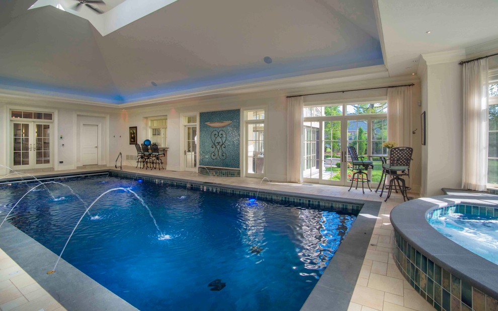 Mid-sized traditional indoor rectangular lap pool in Milwaukee with a hot tub and natural stone pavers.