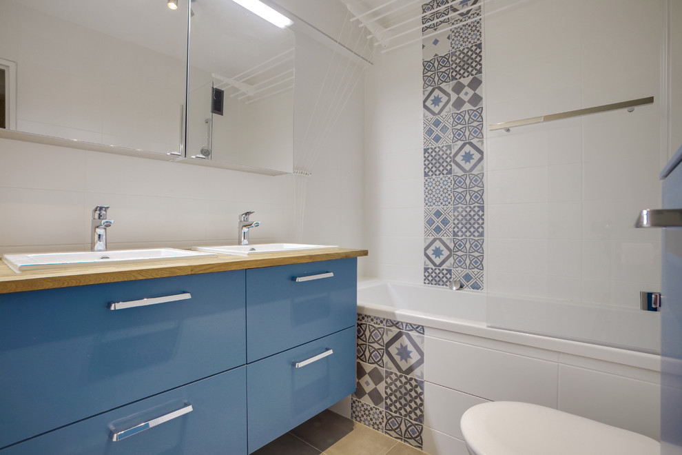 This is an example of a mid-sized contemporary kids wet room bathroom in Paris with an undermount tub, a wall-mount toilet, white tile, ceramic tile, white walls, an undermount sink, wood benchtops and grey floor.