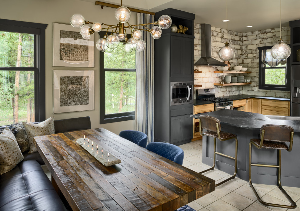 Design ideas for a large eclectic u-shaped eat-in kitchen in Denver with a farmhouse sink, flat-panel cabinets, light wood cabinets, soapstone benchtops, white splashback, ceramic splashback, stainless steel appliances, ceramic floors, beige floor and black benchtop.